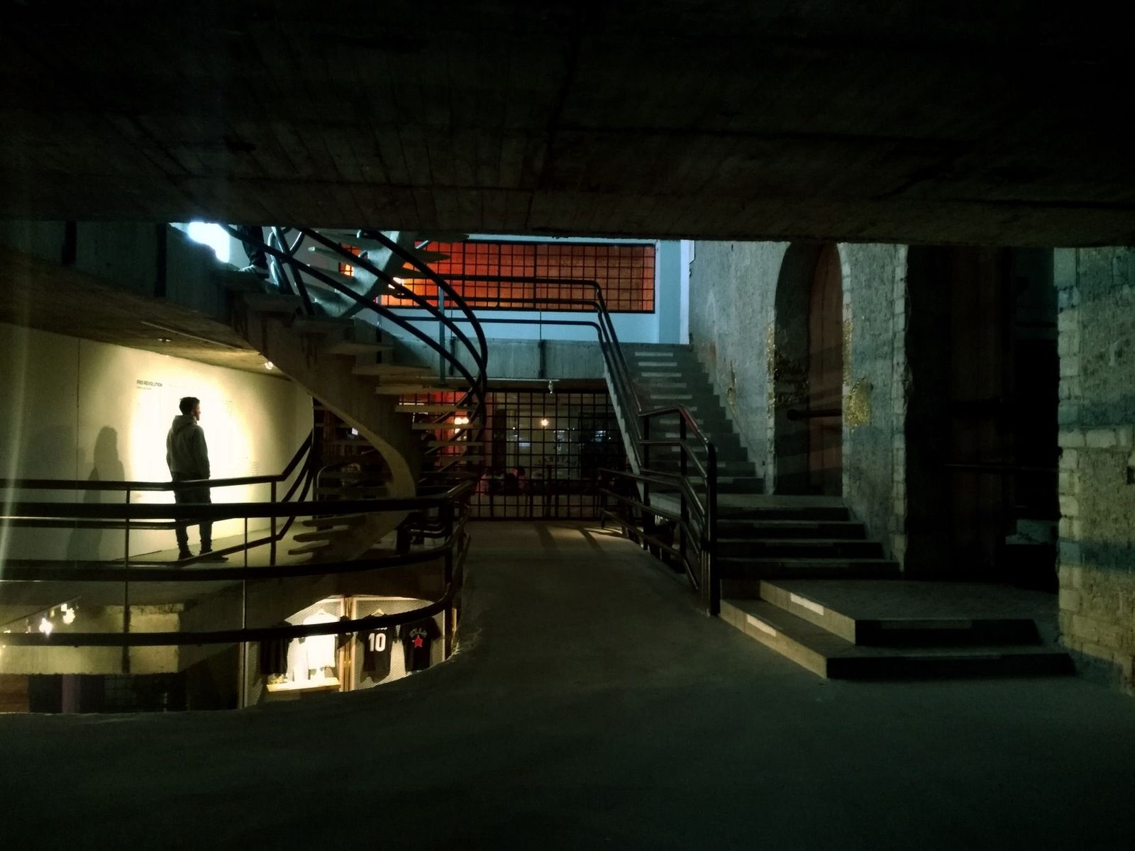 Concrete and metal interior space featuring modern stairs and silhouette of a man.