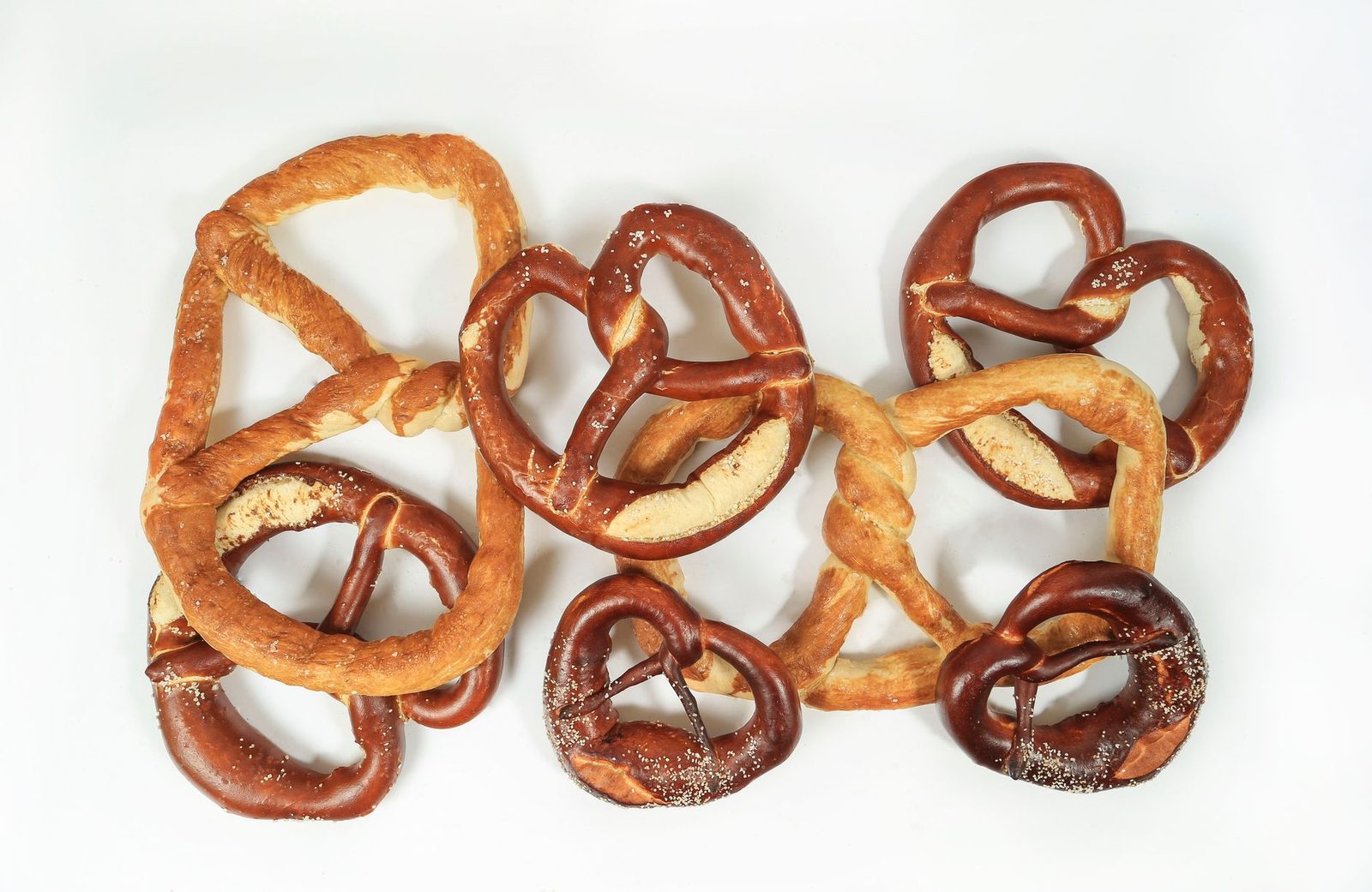 Top view of assorted fresh and salty pretzels on a white background, perfect for snack-themed photography.