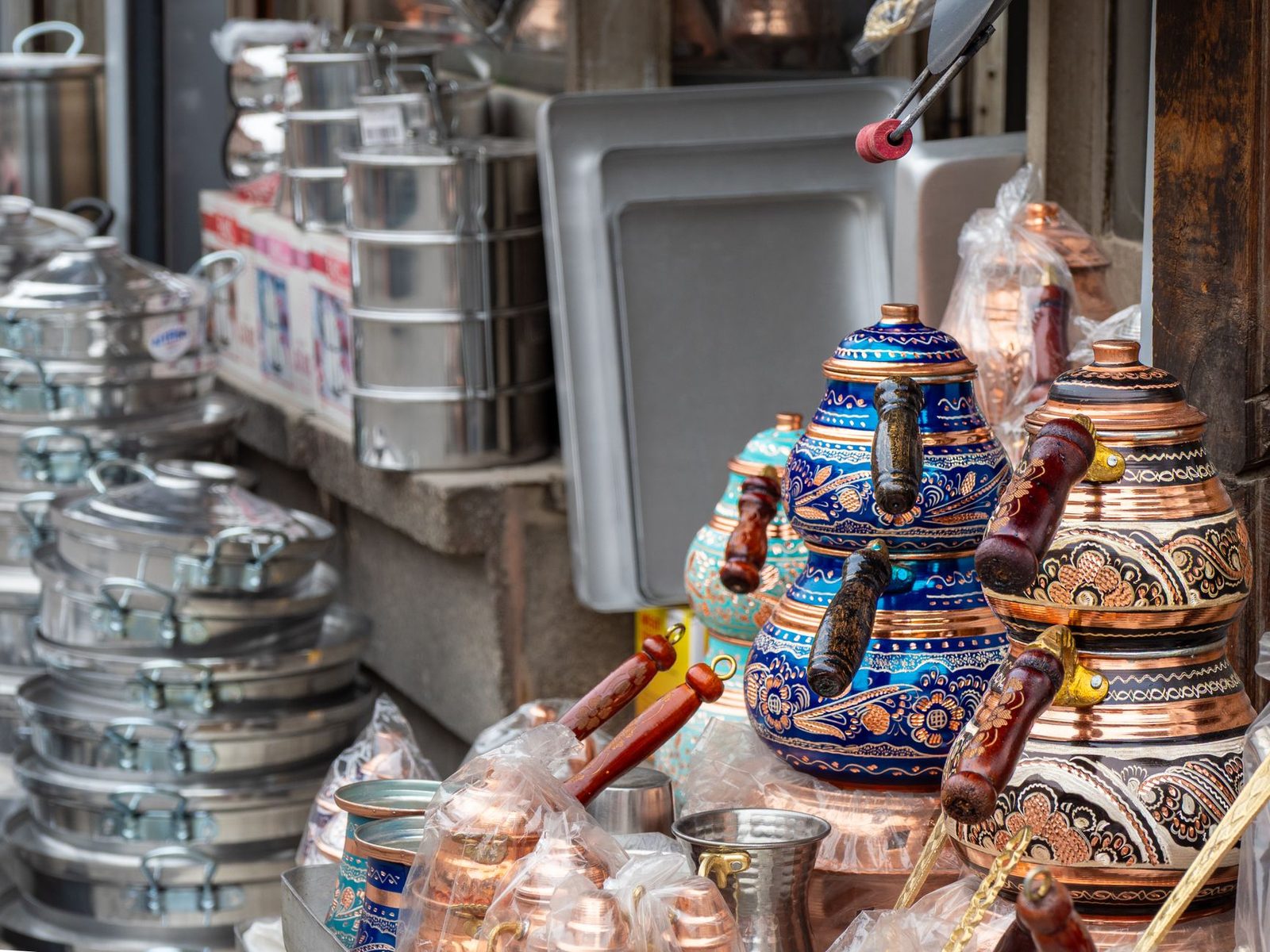 Vibrant traditional copper kettles with ornate designs showcased at an outdoor market, ideal for cultural and trade themes.