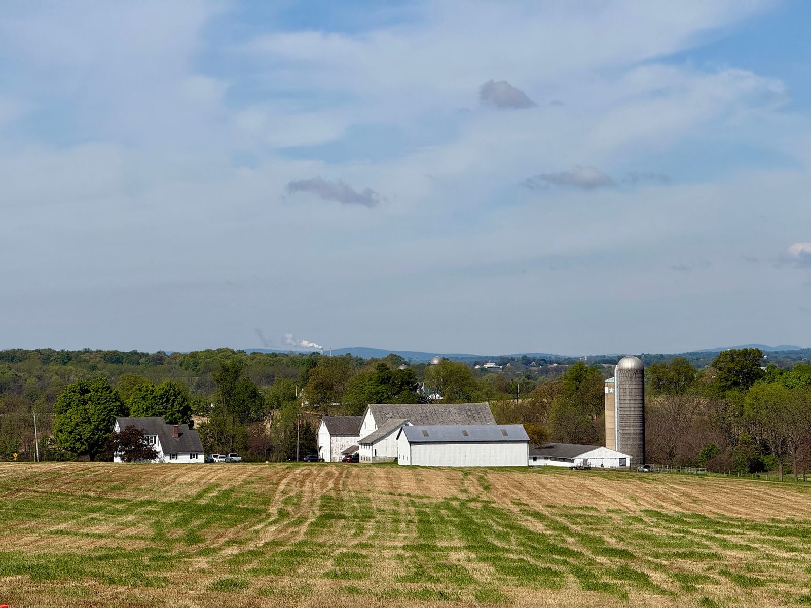 A scenic rural farm landscape with silos and barns in Pennsylvania under a blue sky.