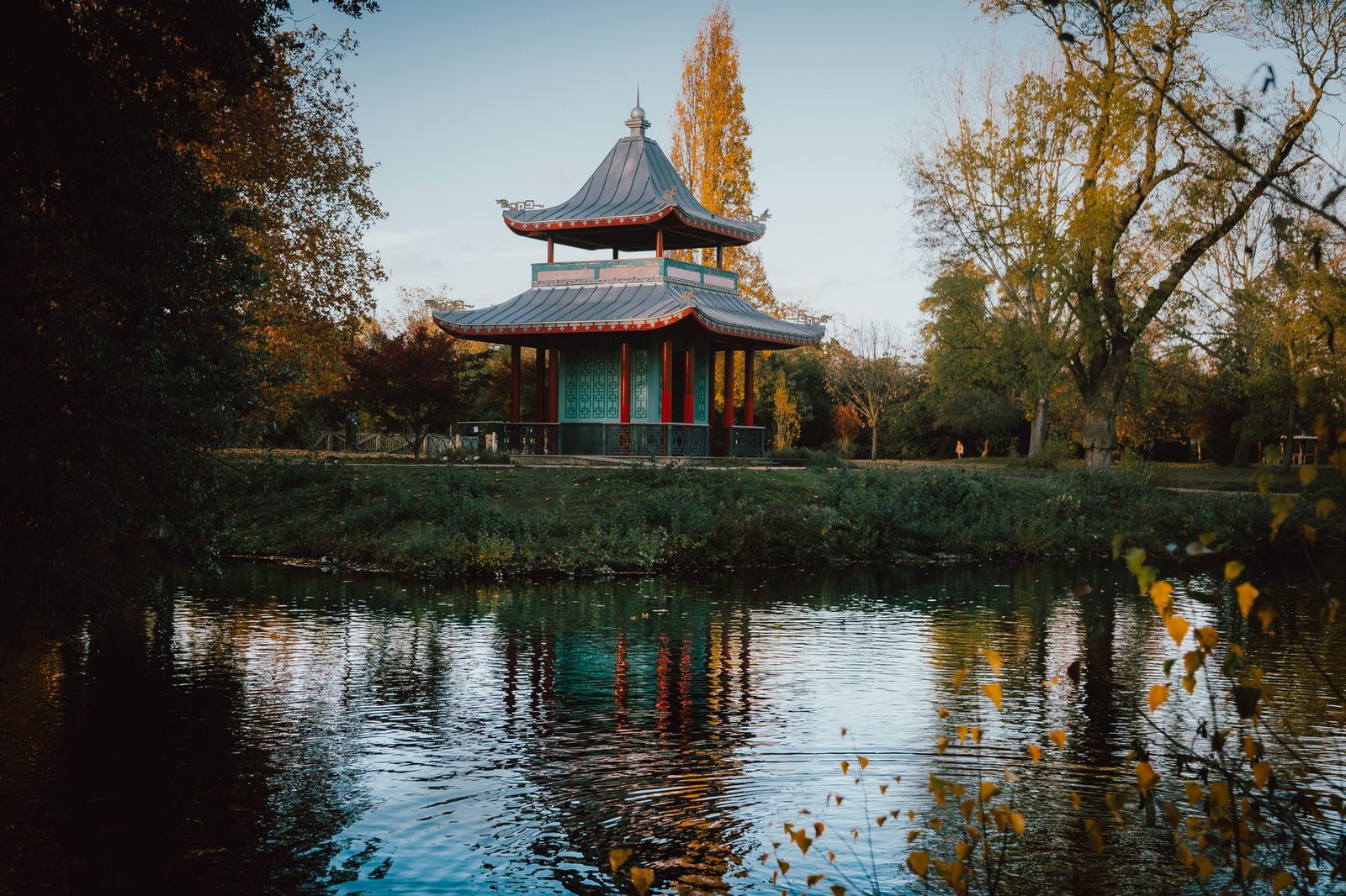 Beautiful autumn scene with a traditional pagoda reflecting on a calm lake surrounded by vibrant foliage.