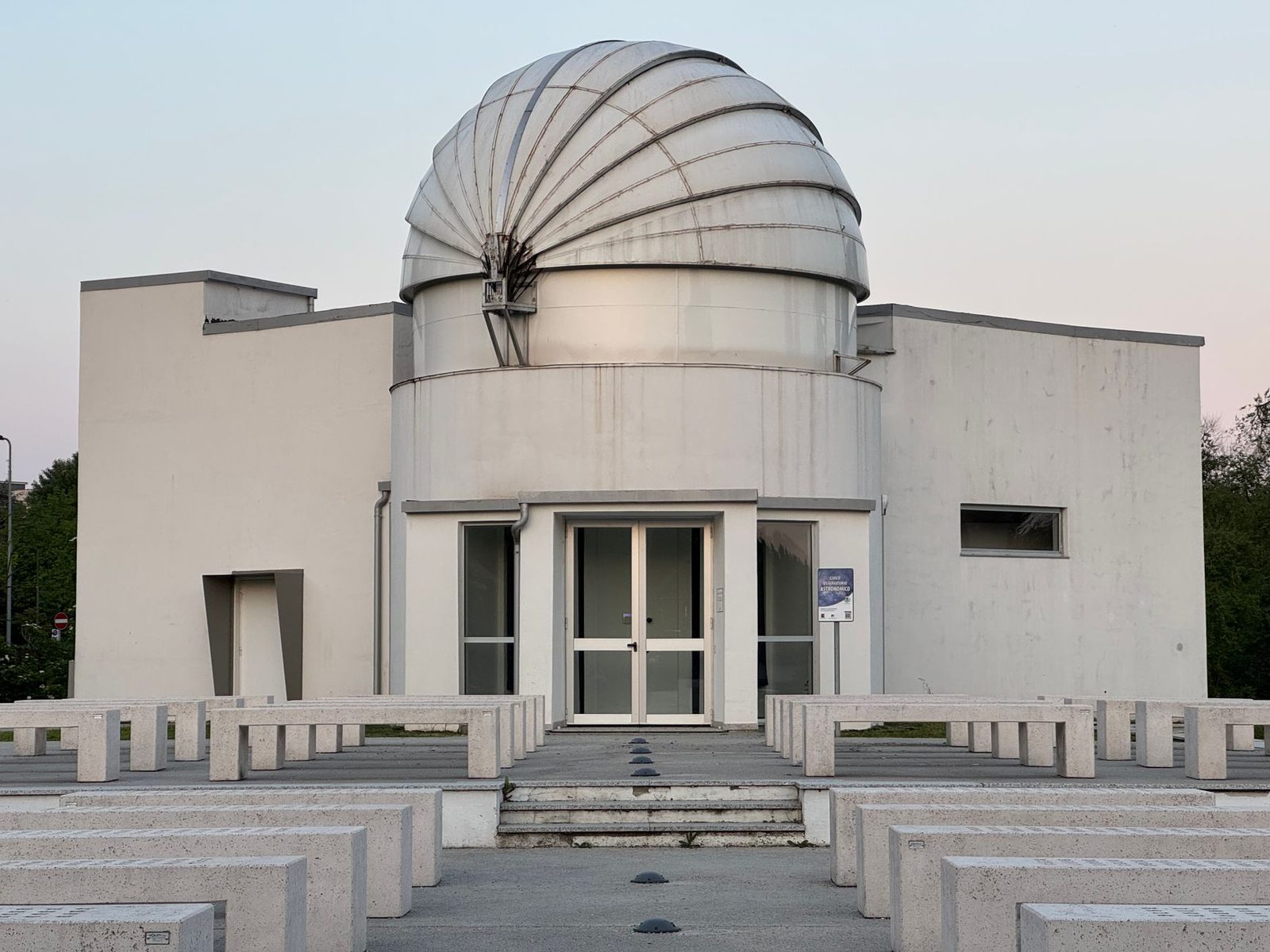 A modern observatory building with a unique dome design in an urban environment.