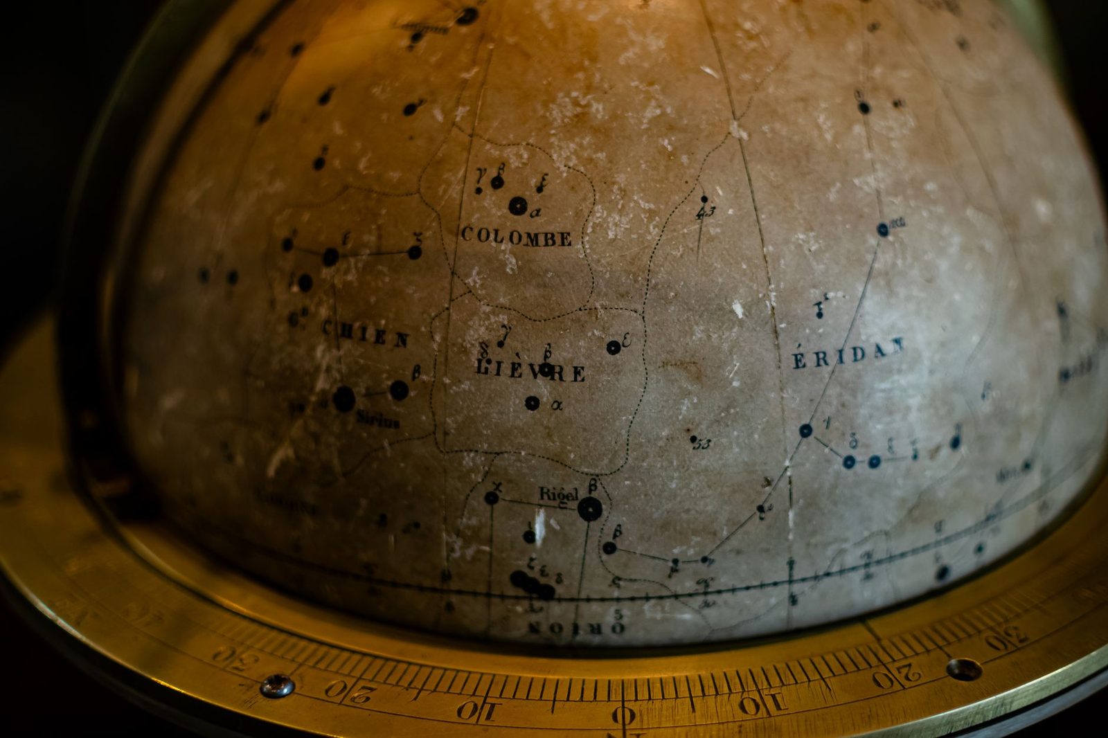 A close-up of an antique globe featuring constellations like Colombe and Eridanus.