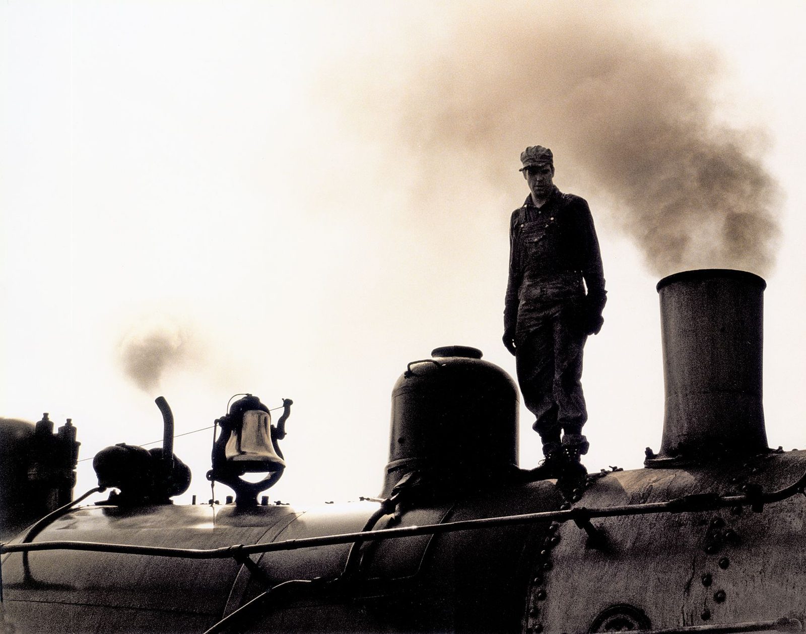 A historic steam locomotive with visible smoke and an engineer in silhouette in Strasburg, Pennsylvania.
